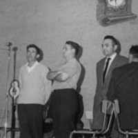 Oholtza: Lazkao Txiki mikrofono aurrean kantuan, aldamenean zutik XX eta Alfonso  Irigoien gai-jartzailea. Eserita, xx . Epailea eserita lepoz. --