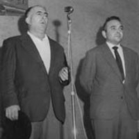 Oholtzan, XX gorputz osoz mikrfono aurrean kantuan. Aldamenean, Alfonso Irigoien  gai-jartzailea --